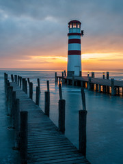 Lighthouse at jetty on the lake in winter