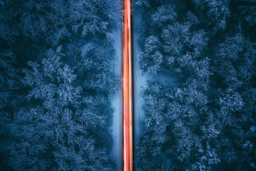 Aerial view of night winter road and cars passing by  forest in mountains. drone shot