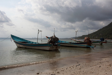 Fototapeta na wymiar Long-tail boats under cloudy sky in harbor of Koh Phangan island, Thailand