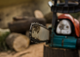 Lumberman using chainsaw sawing dry wood lying on ground.