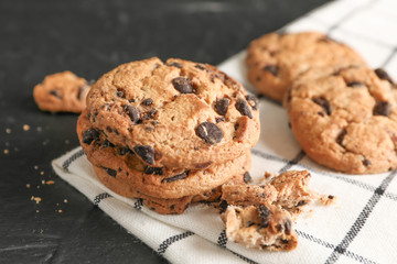 Tasty chocolate chip cookies on napkin and wooden background