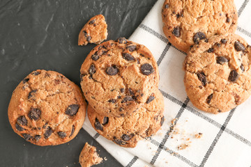 Stack of tasty chocolate chip cookies on napkin and wooden background, top view. Space for text