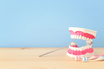 Dental care tools use for dentist and plastic teeth model in the clinic. Wooden blue background.