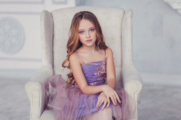 Fototapeta premium portrait of beautiful caucasian little girl wearing dress, sitting on chair