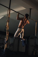 Shirtless athlete doing pull ups on the bar
