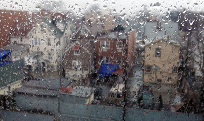 Row of houses seen through a window with rain drops