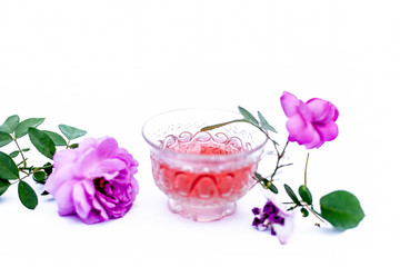 Fototapeta na wymiar Close up view of organic fresh rose tea in a transparent glass cup isolated on white with raw roses.