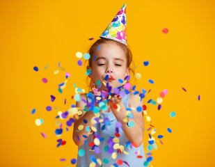 happy birthday child girl with confetti on yellow background.