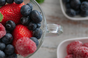 glass cup with berries, blueberries, raspberries, strawberries, and mint.On the wooden table light