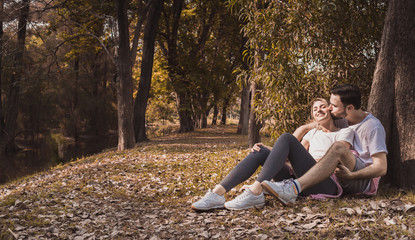 a lovely couple cuddling in a park with copy space in fall season