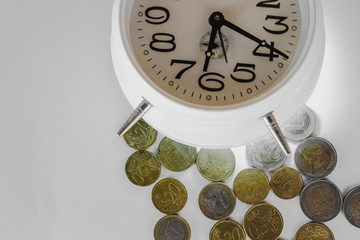 Gold coins on a white background are illuminated by the light of the bottom of the alarm