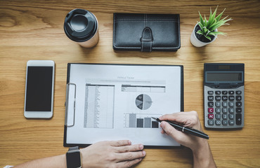 Businessman working on a graph document financial report and analysis calculation cost with...