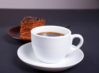 Cup of coffee with delicious piece of chocolate cake on the black table