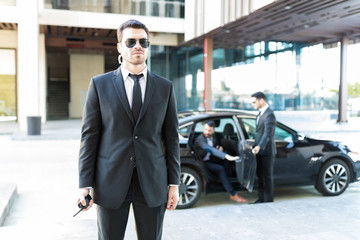 Bodyguard Staying Alert While Colleague Opening Car Door For VIP