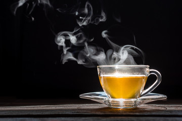 A Cup of freshly brewed  green tea,with steam,warm soft light, dark background.Good morning Tea or Have a happy day message concept.