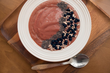 Smoothie bowl with blueberries and chia seeds on wooden background with a spoon