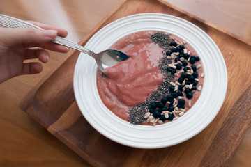 Smoothie bowl with blueberries and chia seeds on wooden background hand spoon