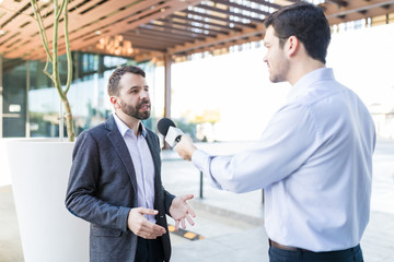 Reporter With Microphone Interviewing Professional