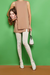 Full length shot of a woman holding her head with natural makeup. The girl is wearing a beige...