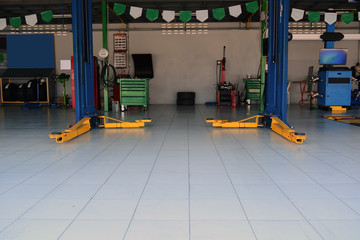 the yellow lift  hand at the bottom of  the lift post and other  accessory machine  at the car repair shop