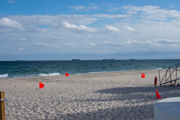 wide angle view of a beach with ships out on the ocean