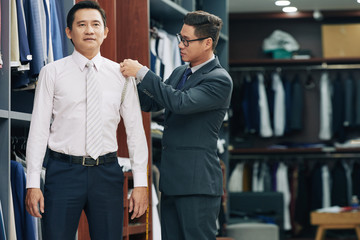 Shop assistant measuring mature man to determine his size