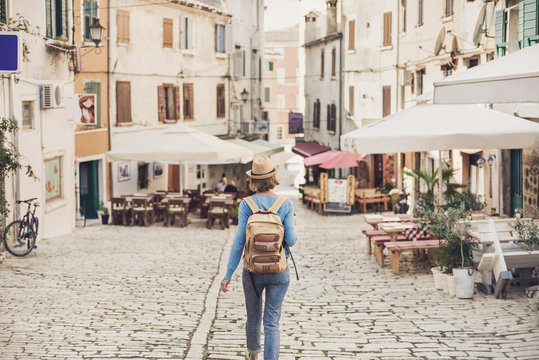Fototapeta Tourist girl walking in the city during vacation. Cheerful woman traveling abroad in summer. Travel and active lifestyle concept