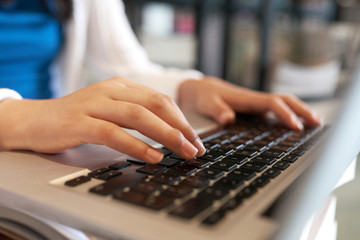 Hands of college student typing on laptop when working on project