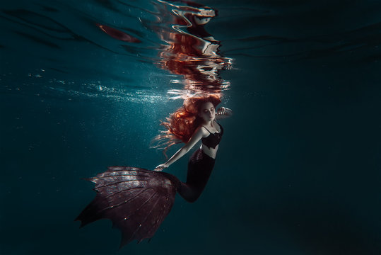 Red hair freediver girl with black mermaid tale