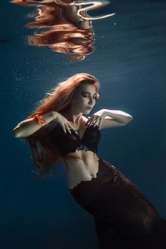Portrait of red haired freediver girl with black mermaid tale
