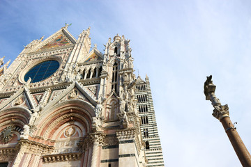 Fototapeta na wymiar Facade of Siena cathedral with the column and she-wolf, symbol of the city at winter morning, Tuscany, Italy