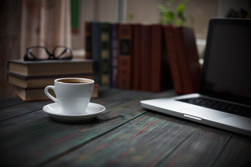 A cup of coffee in the workplace on a wooden table.