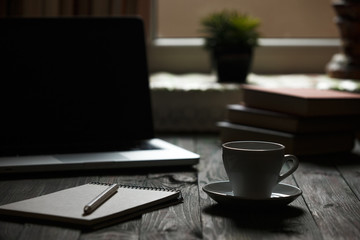 A cup of coffee in the workplace on a wooden table.
