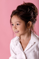 Fototapeta premium Cute smiling little girl in white shirt with hairstyle