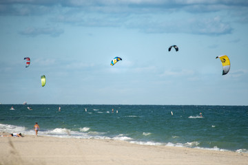 wide angle view from the beach of kite surfers at sea with their colorful kites blowing in the wind