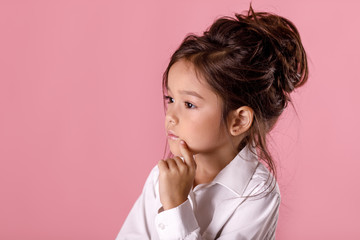 beautiful doubtful, thoughtful little girl in white shirt with hairstyle
