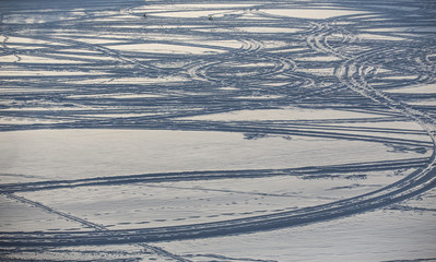 Traces of skis and snowmobiles on the surface of a winter lake