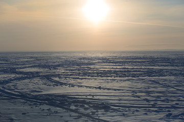 Traces of skis and snowmobiles on the surface of a winter lake