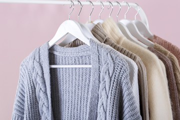 Warm knitted clothes hanging on a rack
