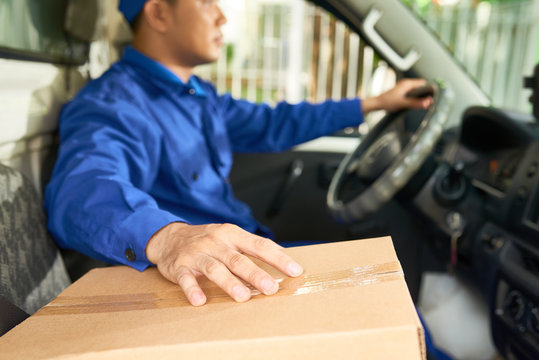 Courier driving car with package on front sit