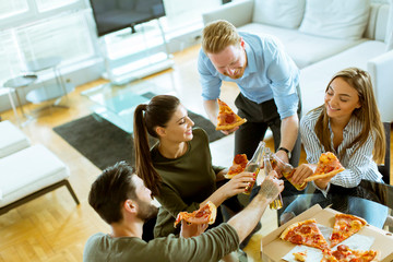 Young people eating pizza and drinking cider in the modern interior