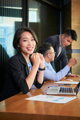Positive smiling Asian business lady working in office with her team