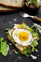 Bran toast with salad mix and fried egg on top. Healthy breakfast presented on a stone board. Keto diet. Keto breakfast or snack.