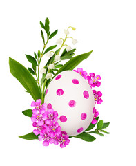 Pink yarrow flowers and Easter painted egg with green grass and lily of the valley