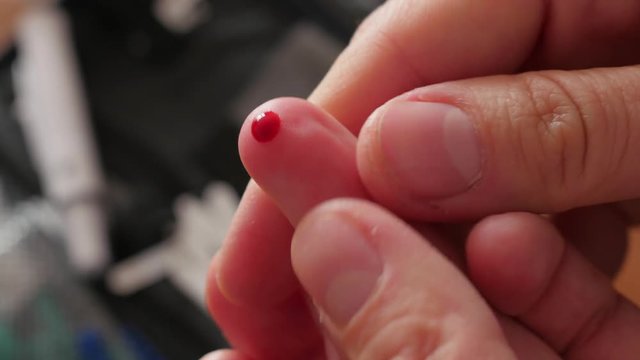 finger pricking to measure blood glucose, smearing blood on finger