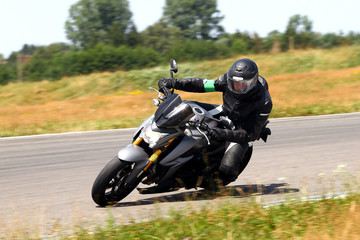 A man on a motorcycle in a cooking suit is leaning into a bend