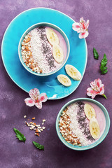 Yogurt with chia seeds, coconut flakes, almonds and fresh banana. Healthy dietary breakfast decorated with flowers. View from above.