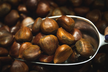 Hazelnuts with bark vegan together and accumulated being caught in the market with the metal shovel and woman's hand