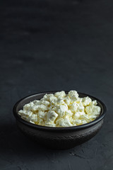Homemade cottage cheese in a black ceramic bowl