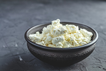 Homemade cottage cheese in a black ceramic bowl